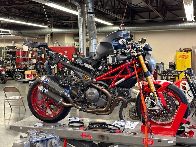 Front right quarter view of my motorcycle on its work lift, disassembled with tools and parts nearby