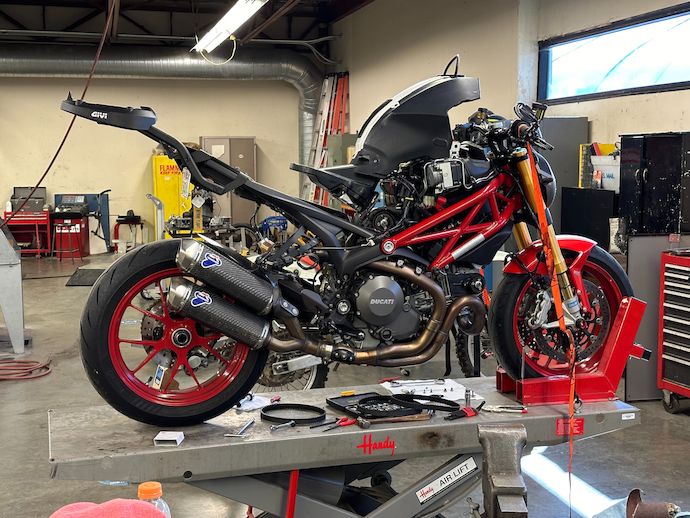 Rear right quarter view of my motorcycle on its work lift, disassembled with tools and parts nearby