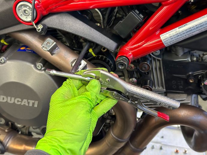 Locking pliers around top of T-handle extending into timing belt tensioner screws